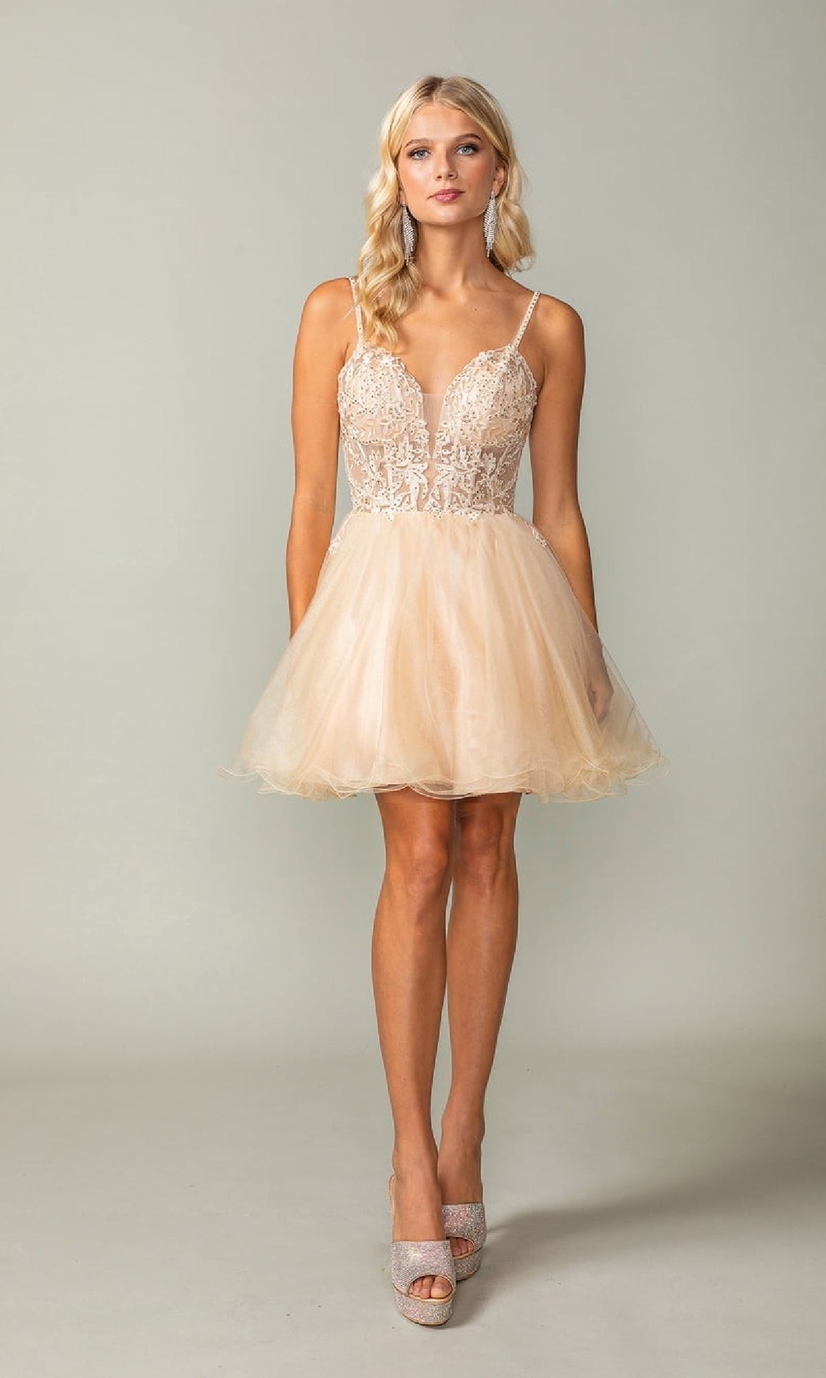 Woman wearing a short champagne colored dress with a plain background
